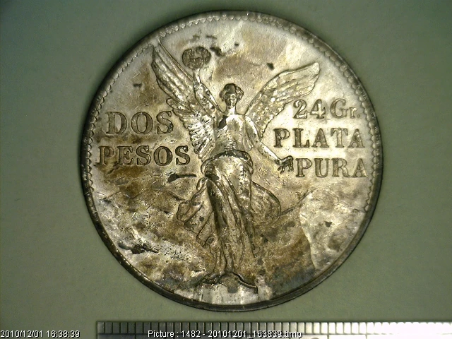 Reverse of the Mexican 1921 silver two pesos coin showing Winged Victory and the 24 grams pure silver inscription.