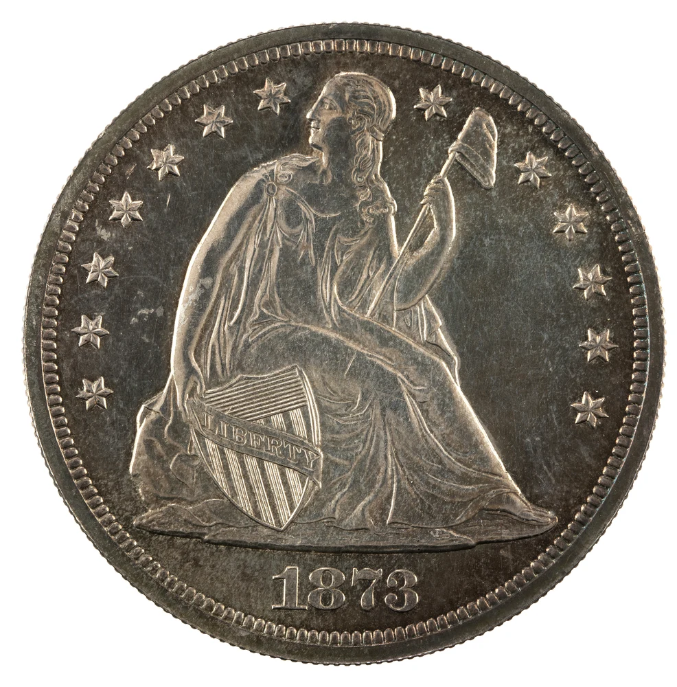 Liberty Seated Silver Dollar obverse — 1873 Philadelphia dollar with motto, genuine NNC specimen; both faces are illustrative, not a customer grading or authentication result.