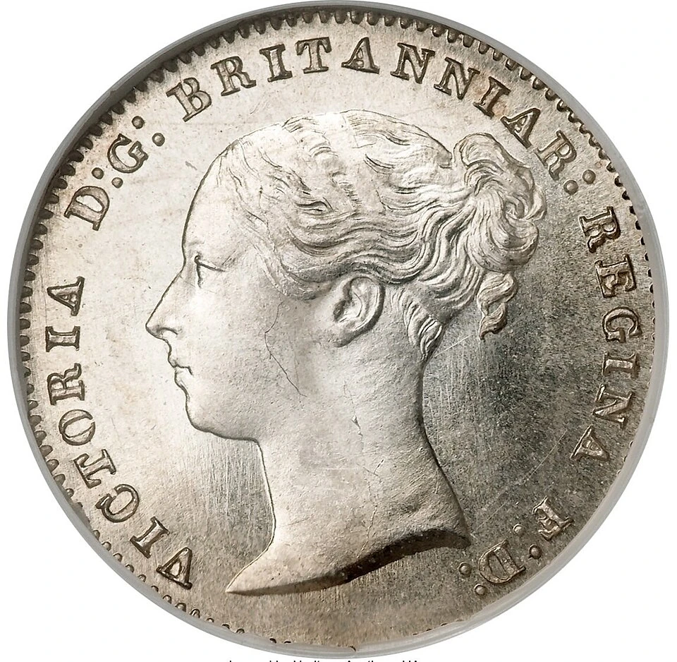 1858 British sterling threepence obverse — Victoria’s young head faces left, with her hair tied behind the head and a surrounding royal legend.