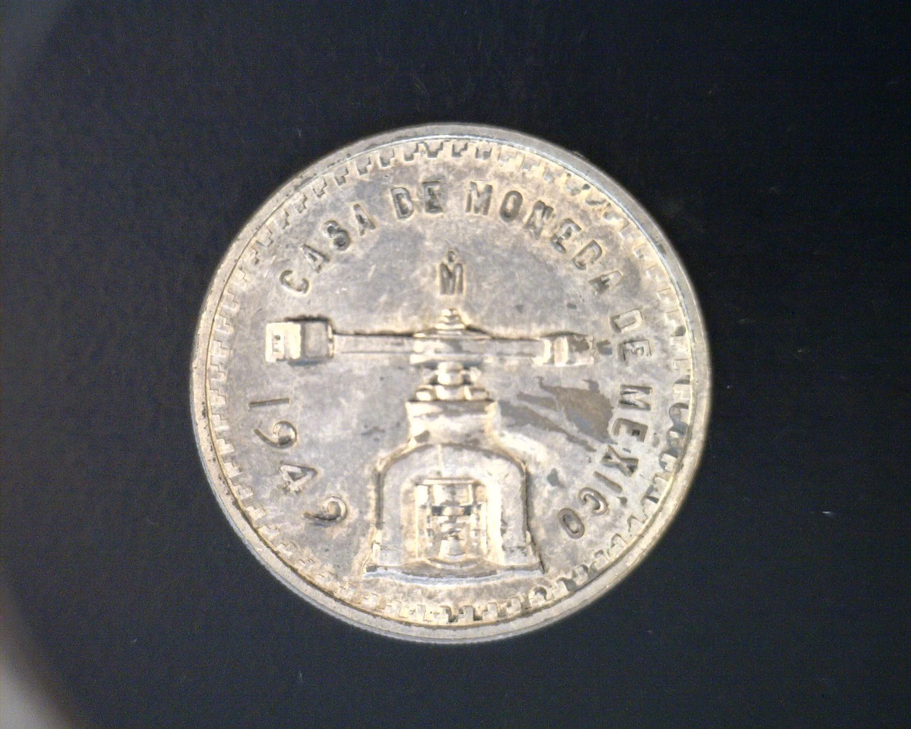 Obverse of a Mexican 1949 sterling silver Onza showing a coin press, mint name and date.